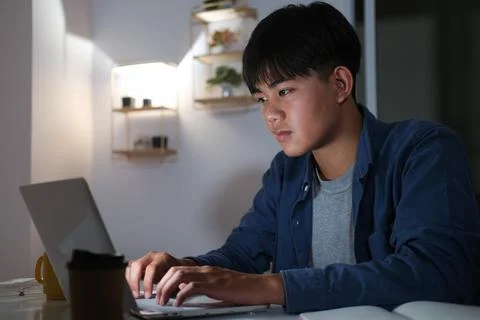Young collage man learning online at night at his home. 写真素材