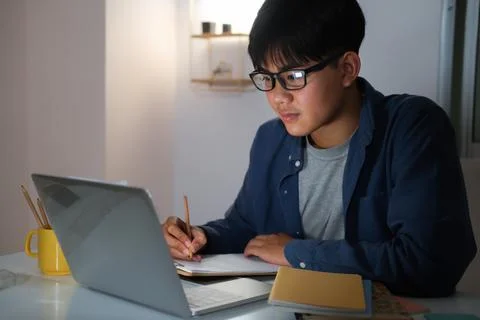 Young collage man learning online at night at his home. Stock Photos