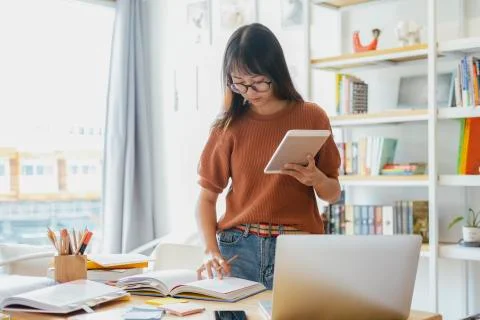 Young collage student using computer and mobile device studying online. Stock Photos