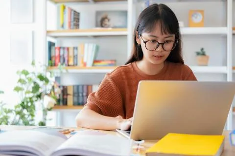Young collage student using computer and mobile device studying online. Stock Photos