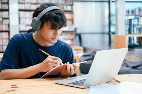 Young collage student using computer and mobile device studying online. Stock Photos