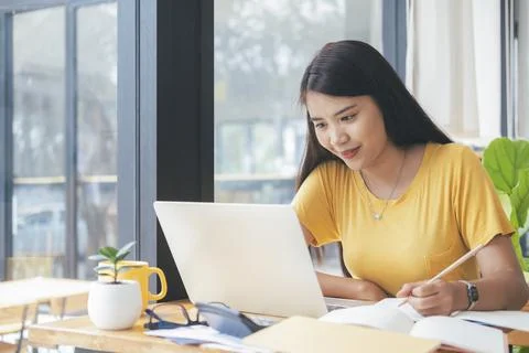 Young collage student using computer and mobile device studying online. Stock Photos