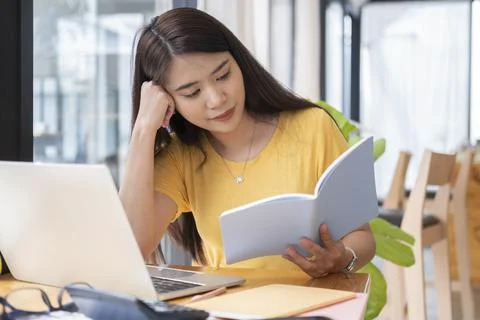 Young collage student using computer and mobile device studying online. Stock Photos