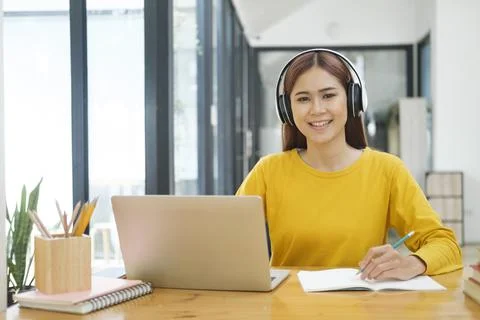 Young collage student using computer and mobile device studying online. Stock Photos