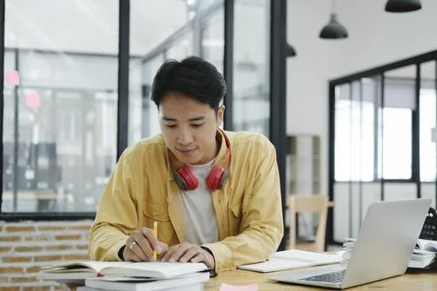 Young collage student using computer and mobile device studying online... Stock Photos