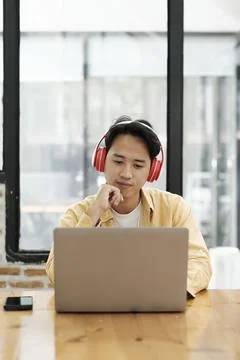 Young collage student using computer and mobile device studying online... Stock Photos