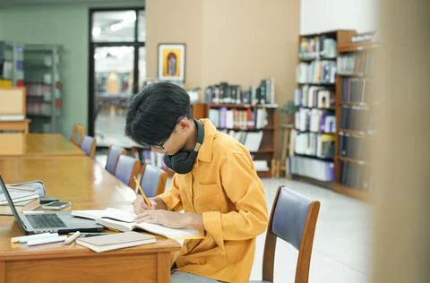 Young collage student using computer and mobile device studying online. Stock Photos