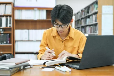 Young collage student using computer and mobile device studying online. Stock Photos