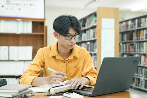Young collage student using computer and mobile device studying online. Stock Photos