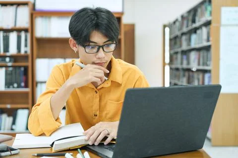 Young collage student using computer and mobile device studying online. Stock Photos