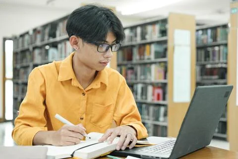 Young collage student using computer and mobile device studying online. 写真素材