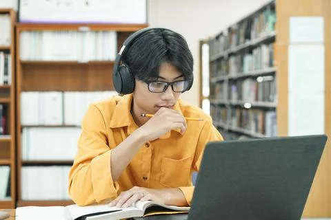Young collage student using computer and mobile device studying online. Stock Photos