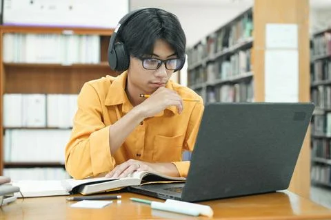 Young collage student using computer and mobile device studying online. Stock Photos