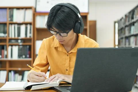 Young collage student using computer and mobile device studying online. Stock Photos