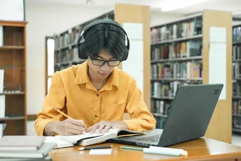 Young collage student using computer and mobile device studying online. Stock Photos