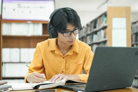 Young collage student using computer and mobile device studying online. Stock Photos