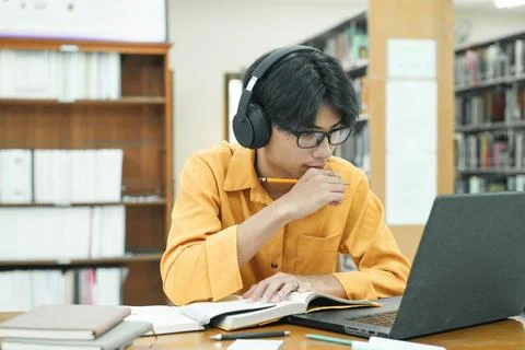 Young collage student using computer and mobile device studying online. Stock Photos