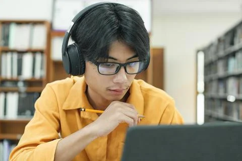 Young collage student using computer and mobile device studying online. Stock Photos