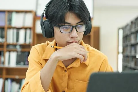 Young collage student using computer and mobile device studying online. Stock Photos