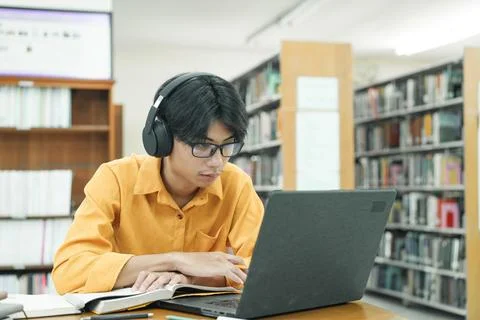 Young collage student using computer and mobile device studying online. Stock Photos