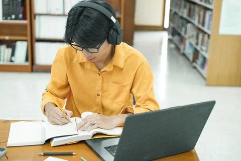 Young collage student using computer and mobile device studying online. Stock Photos
