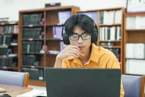 Young collage student using computer and mobile device studying online. Stock Photos