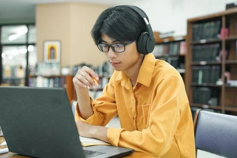 Young collage student using computer and mobile device studying online. Stock Photos