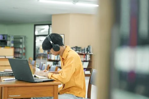 Young collage student using computer and mobile device studying online. Stock Photos