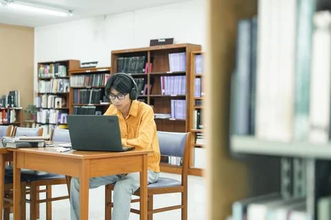 Young collage student using computer and mobile device studying online. Stock Photos