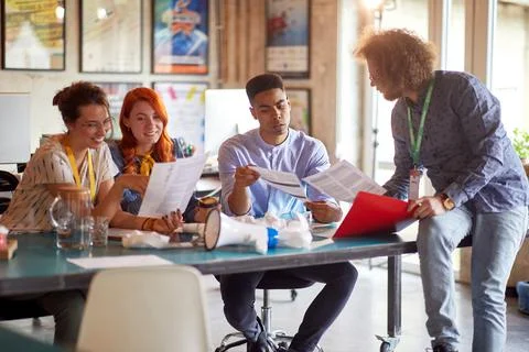 Young colleagues are inspecting some documents at desk in the office Stock Photos