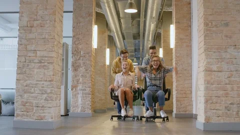 Young Colleagues Having Fun and Riding Office Chairs in Hallway Vidéo 126135271