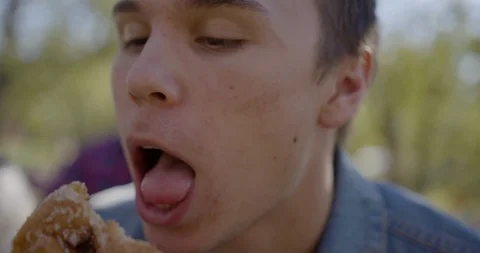 Young College student, stuffing a donut into his face slow motion Stock Footage 94551673