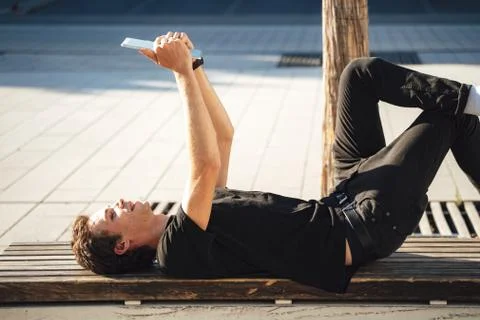 Young college student using digital tablet while lying on bench at campus Stock Photos