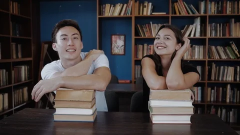 Young college students at the library studying together, they are smiling at Stock Footage 98558445