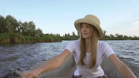 Young concentrated female rower using paddles to sail rusty old boat on calm Stock Footage 95188435