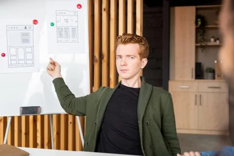 Young confident developer of mobile software pointing at papers with sketches Stock Photos