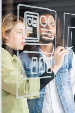 Young confident female software developer pointing at sketch of new application Stock Photos