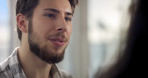 Young confident men with beard and brown hair is talking to a woman in a room Stock Footage 92093785