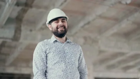A young construction engineer in a helmet looks at the camera and smiles. Great Stock Footage 130775255