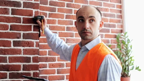 A young construction engineer makes room measurements with a laser roulette Stock Footage 85925455