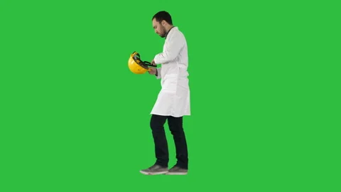 Young construction engineering student walking and putting cap on on a Green Stock Footage 98933257