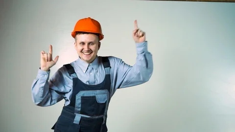 Young construction worker in hard hat on a white background funny dancing . lol Stock Footage 102778397