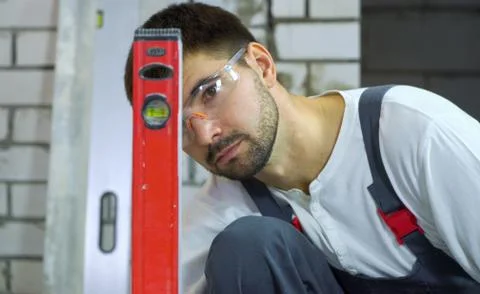Young construction worker looking at bubble level Stock Photos