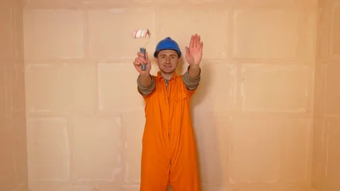 Young constructor in helmet dancing with paint roller Stock Footage 71942051