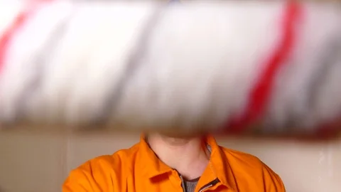 Young constructor looking at the camera and using the paint roller Stock Footage 71941294