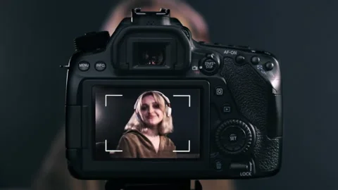 Young content creator blonde talking girl filming herself using a camera on a Stock Footage 152064016