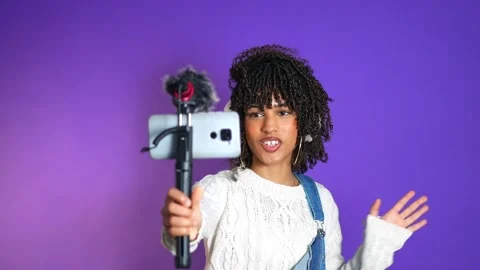 Young content creator recording a video blog on purple background Stock Footage 301369735