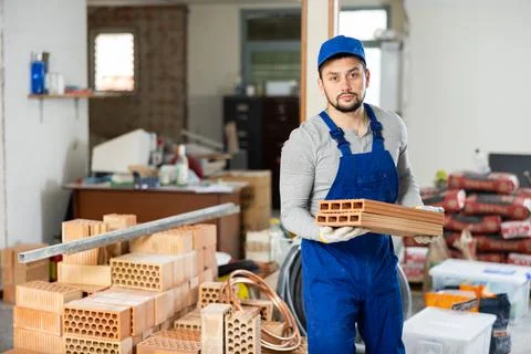 Young contractor stacking bricks on construction site indoors Stock Photos