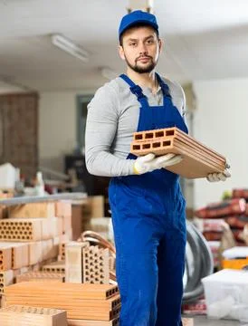 Young contractor stacking bricks on construction site indoors Stock Photos
