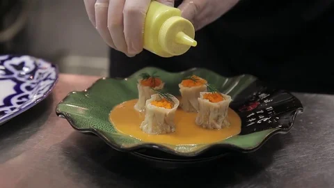 Young cook decorates cooked dish with soy sauce in kitchen of restaurant. Stock Footage 76808458